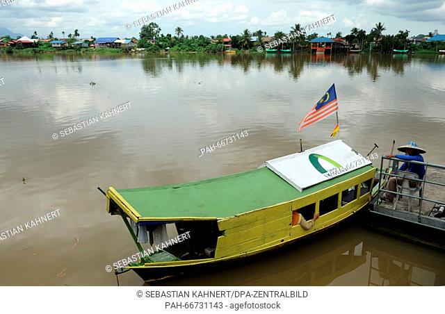 A ferryman is waiting for passengers next to his wooden boat on the shore of the Sarawak River in Kuching, Malaysia, 21 October 2014
