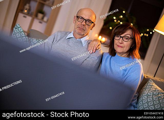 senior couple watching tv at home in evening