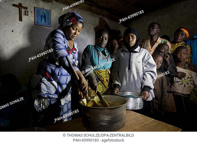 Local health assistant Stefan (L) cooks with women of the village a stew with bananas, beans, potatoes and peanuts to provide a meal for malnourished children...