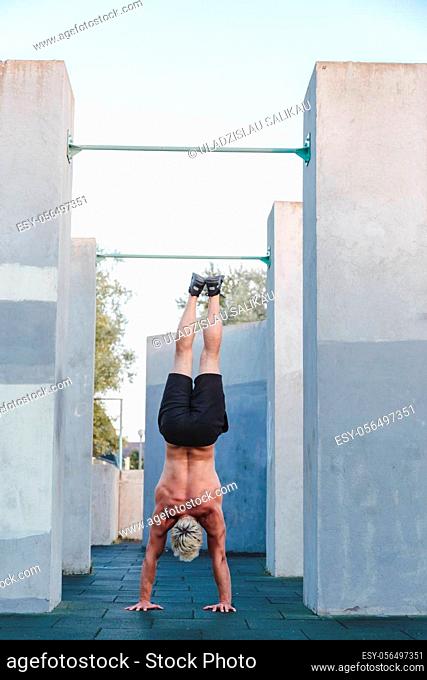 Handstand yoga pose by athlete man on the sport ground outdoors, natural lifestyle photo