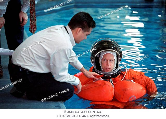 Astronaut Patrick G. Forrester, mission specialist, assisted by crew trainer Adam Flagan, floats in water during an emergency egress training session at the...