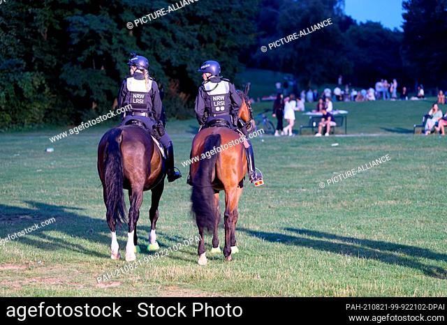 21 August 2021, Cologne: Officers of the state police equestrian squad ride their horses across the meadows at the Aachen pond