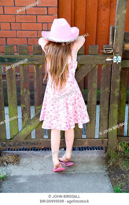 Little girl leaning over a garden gate