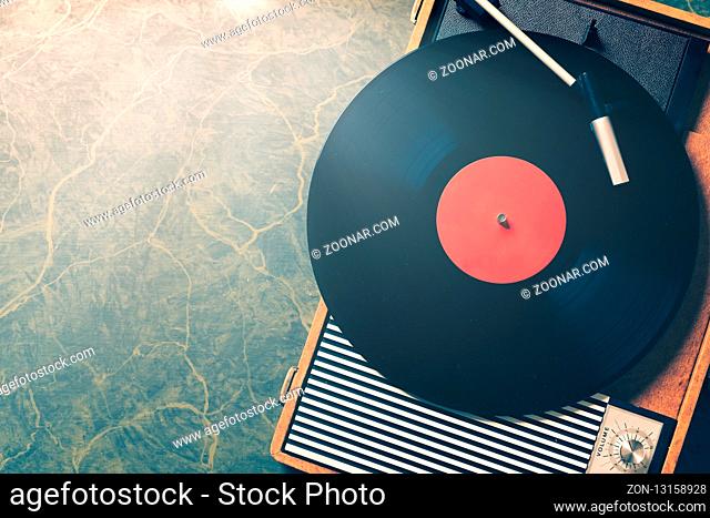 Older Gramophone with a vinyl record on wooden table, top view and copy space, vintage style with split toning