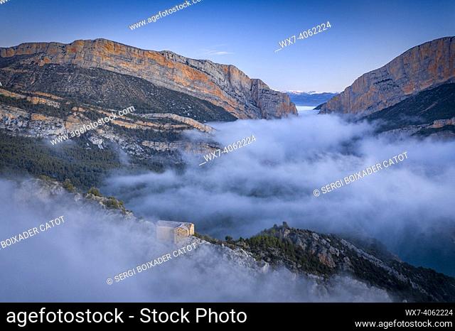 Aerial views of the Congost de Mont-Rebei Gorge and the Santa Quiteria Hermitage in a winter foggy sunrise (Montfalcon, Aragon, Spain, Pyrenees)