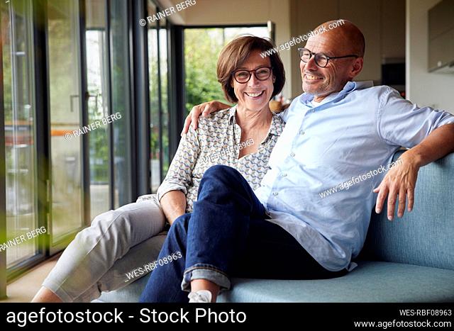 Cheerful senior couple sitting on sofa together at home