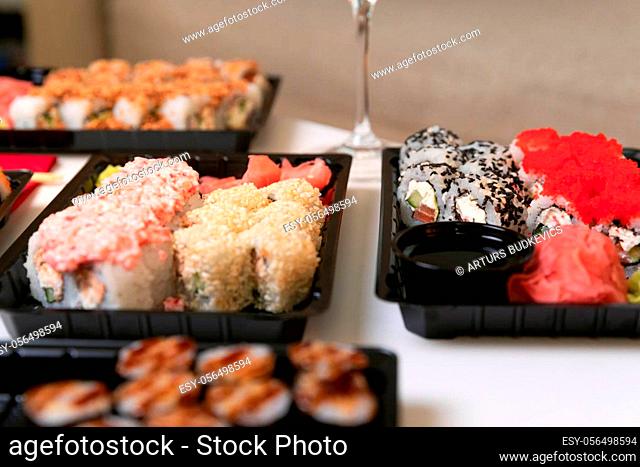 A set of colorful sushi set on a white table with wine in a cozy room