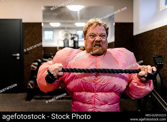 Man wearing pink bodybuilder costume practicing in gym
