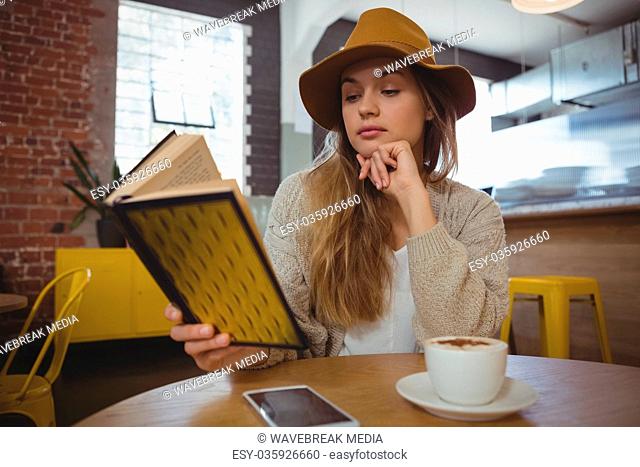 Woman reading book in cafe
