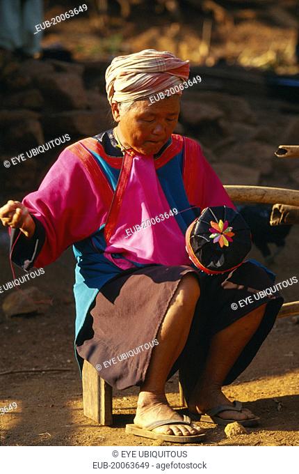 Elderly Lisu woman embroidering a hat for a young boy at her residence