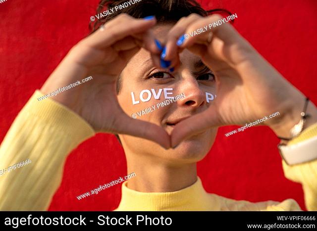 Woman gesturing heart with hands in front of face with text