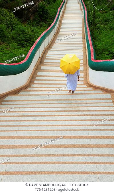 nun walks down long stairs at Wat Phra Phuttabat outside of Khon Kaen, Thailand