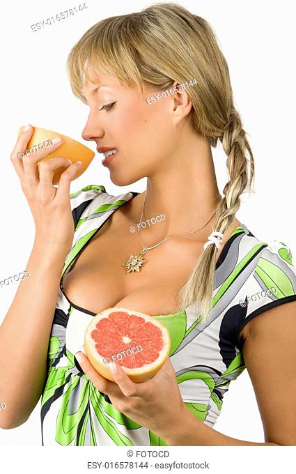 nice and young girl with green dress and braid hair smelling grapefruit