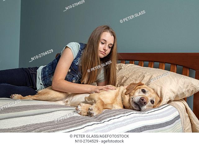 Teenage girl with her pet dog, on her bed