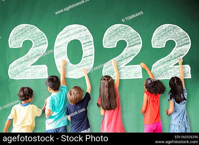 School children drawing 2022 new year on the chalkboard