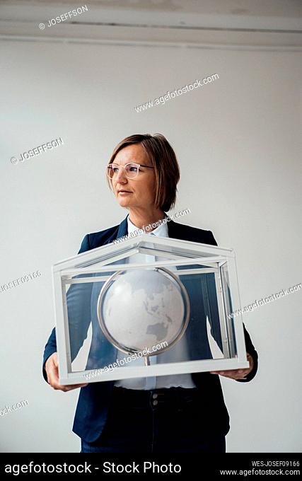 Businesswoman with globe in house shaped glass container