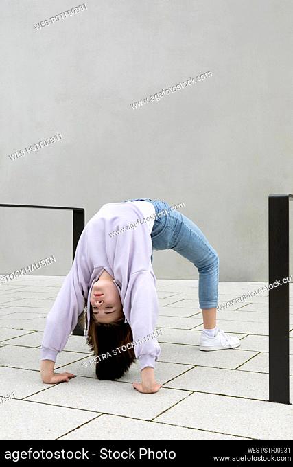 Girl bending over backwards by wall