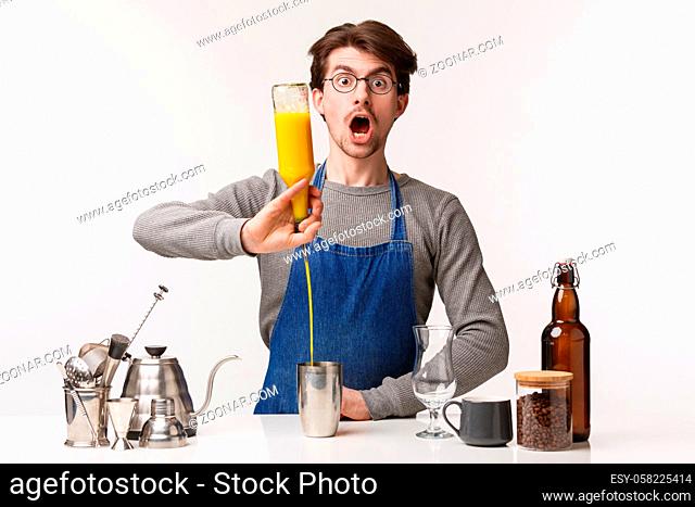 Barista, cafe worker and bartender concept. Portrait of man employee making shocked expression, open mouth and gasping as pouring juice into shaker