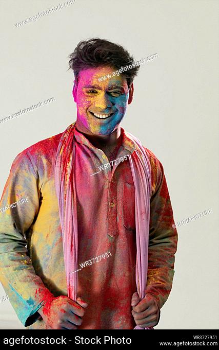 Portrait of a man with colors all over smiling on Holi
