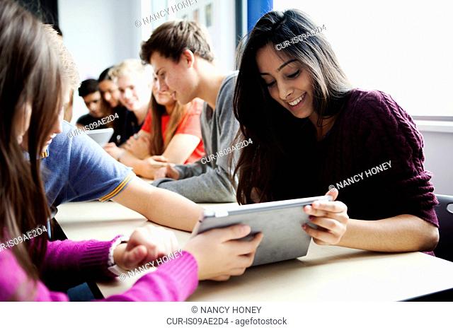 Teenage schoolgirls sitting at desk using digital tablet