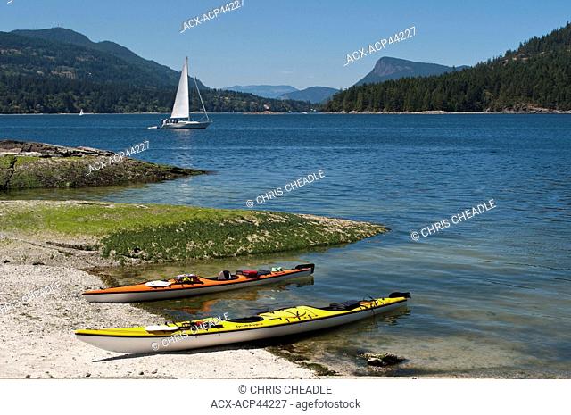 Kayaks and sailboat on Russell Island with view to Fulford Harbour, Saltspring Island, British Columbia, Canada
