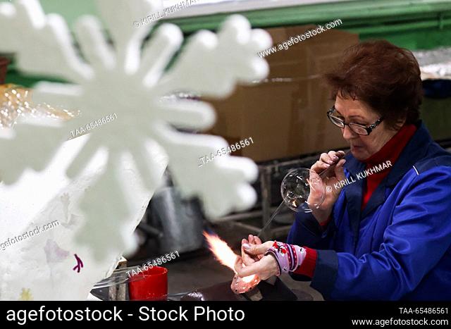 RUSSIA, KRASNOYARSK - DECEMBER 5, 2023: A woman blows glass for baubles at Biryusinka, an enterprise producing handmade Christmas decorations