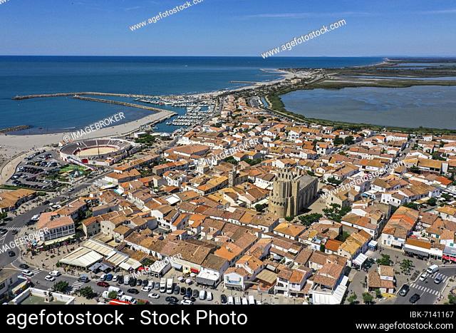 Drone shot, drone photo of Saintes-Maries-de-la-Mer with old town, harbour, the church Notre Dame and the salt fields in the background