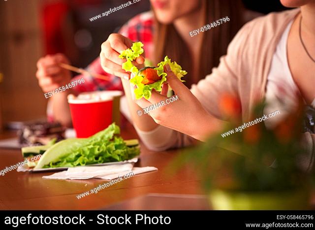 Clseup toned picture of lady eating vegetarian dihes in cafe or restaurant while sitting at wooden table. Vegetarian concept