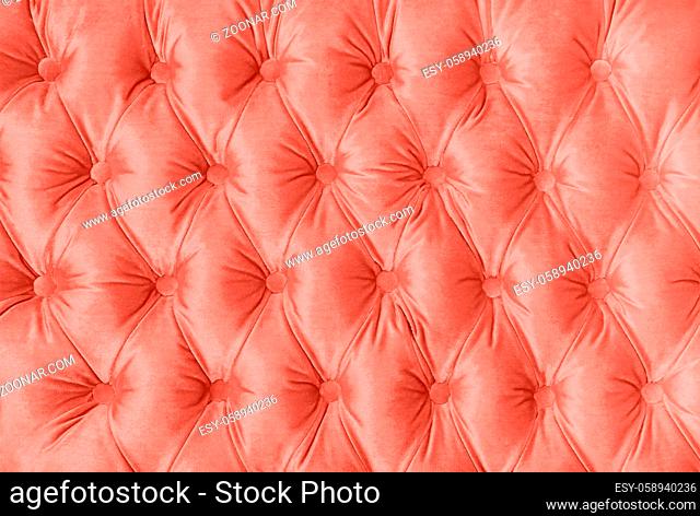 Coral toned pink velvet capitone textile background, retro Chesterfield style checkered soft tufted fabric furniture decoration with buttons, close up