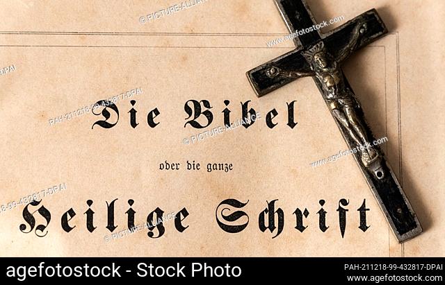 ILLUSTRATION - 17 December 2021, Baden-Wuerttemberg, Rottweil: An old cross can be seen next to the inscription The Bible or the Whole Holy Scripture on the...
