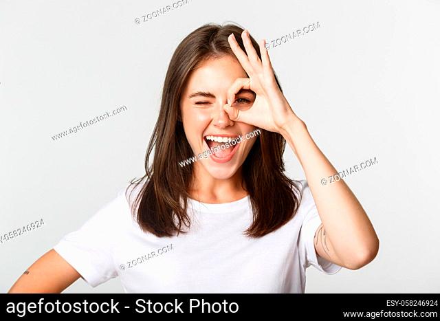 Cheerful attractive girl smiling and showing okay gesture, winking excited
