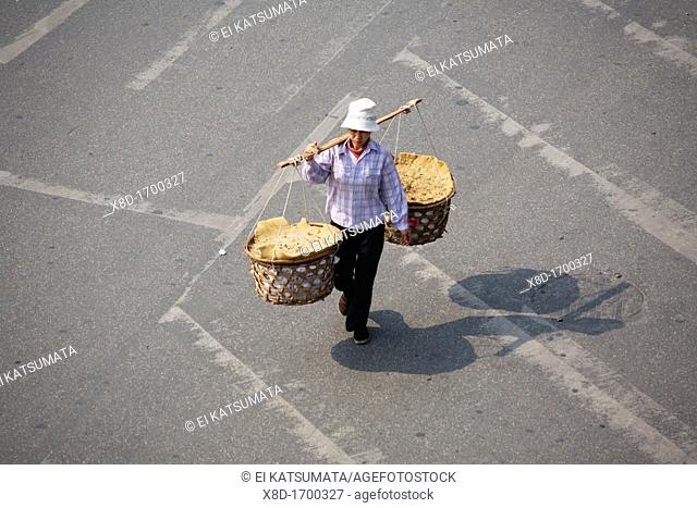 Street vendor with baskets crossing the street, Old Quarter, Hanoi, Vietnam