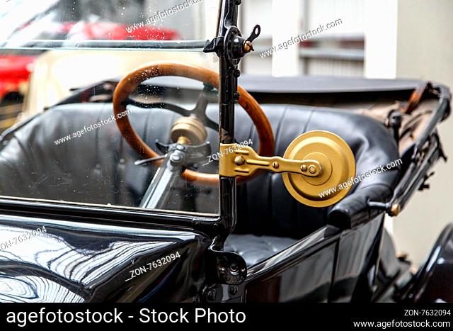 Close up detailed view of steering wheel and seat of nostalgical old black automobile