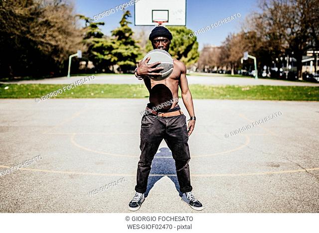 Portrait of barechested basketball player on court