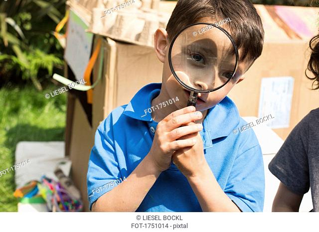 Portrait of cute boy with magnifying glass in back yard