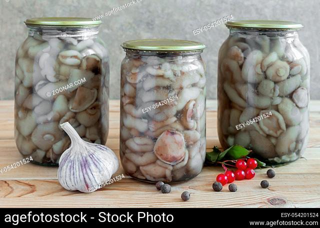 Home preservation of products: glass jars with pickled mushrooms with spices closed