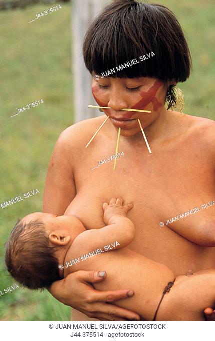 Yanomami indian woman brest feeding baby outdoor