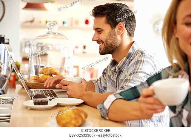 Young man with laptop in a cafe