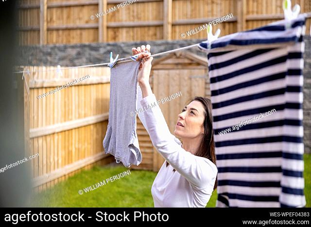 Woman hanging up laundry outside house
