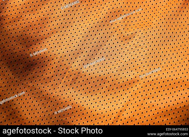 Sport clothing fabric texture background. Top view of orange polyester nylon cloth textile surface. Colored basketball shirt with free space for text