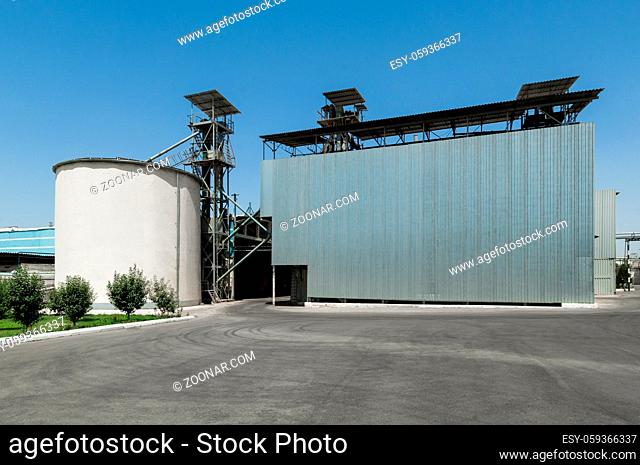 storage tank and a building on a farm under a blue sky. heavy industrial plant