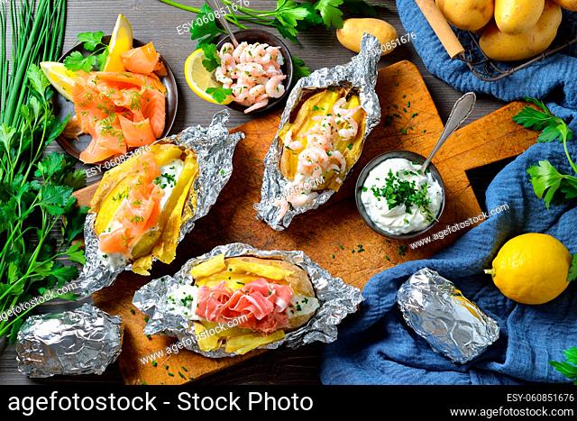 Various kinds of baked potatoes with herb sour cream: topped with smoked salmon, Italian ham and shrimps