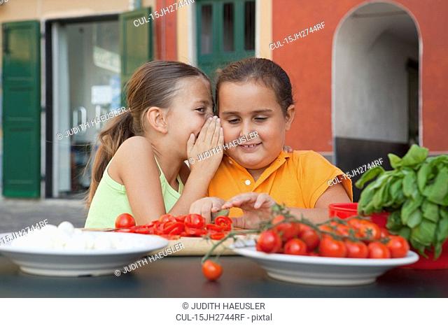 girls whispering whilst preparing food