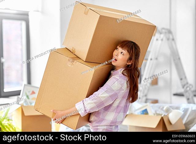 woman holding heavy boxes and moving to new home