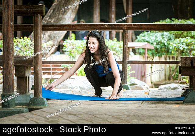 A girl laying out her yoga mat, woman spreading her yoga mat outdoors