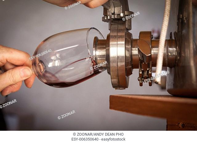 Vintner Pours Taste of Wine from Barrel into Glass