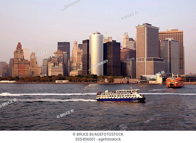 A tour boat and Staten Island Ferry with the cityscape of Lower Manhattan in background, New York City. USA