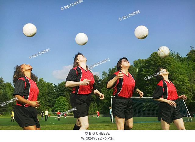 Four young female soccer players heading balls