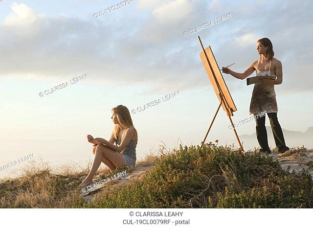 Young man painting with young woman