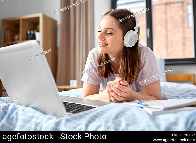 happy student girl in headphones learning at home